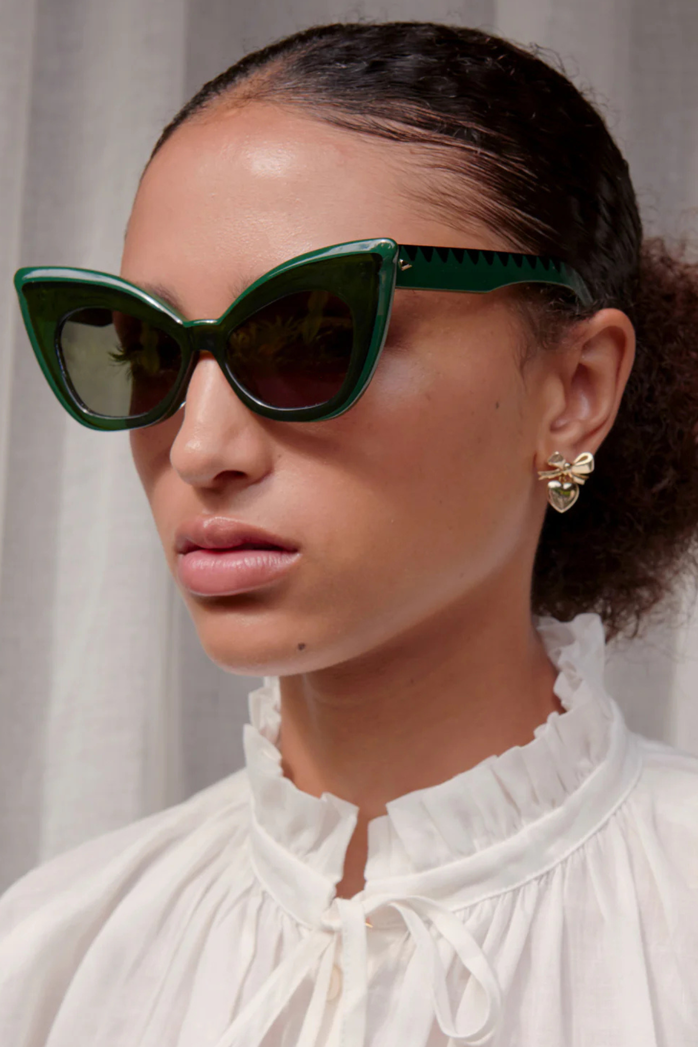 close up of face of a woman wearing emerald green Andromeda (extreme cat-eye) sunglasses